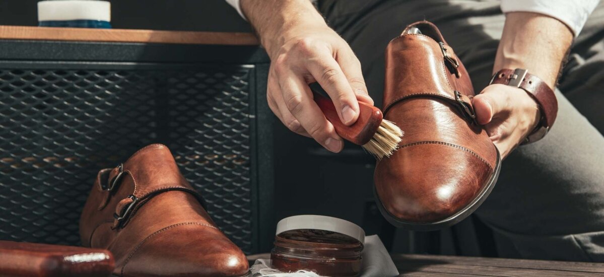 Ročna nega usnjenega čevlja z uporabo krtače in kreme za vzdrževanje, prikaz pravilnega čiščenja in osveževanja obutve doma