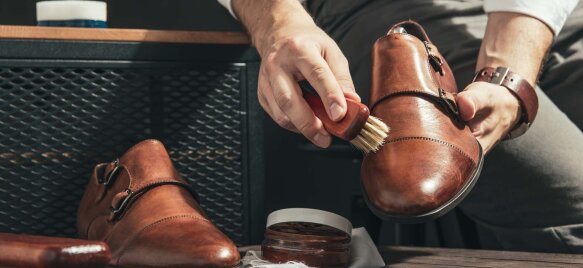 Ročna nega usnjenega čevlja z uporabo krtače in kreme za vzdrževanje, prikaz pravilnega čiščenja in osveževanja obutve doma